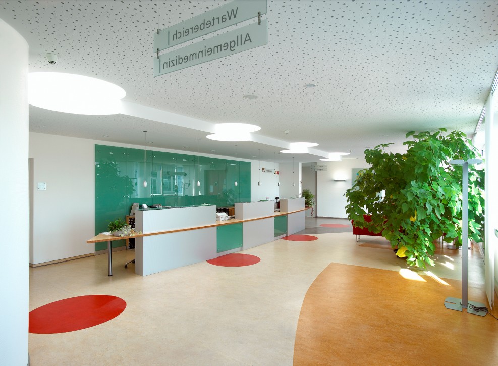 Heller Empfangsbereich mit Linoleum-Naturboden in verschiedenen Farbzonen, Pflanzen und moderner Einrichtung